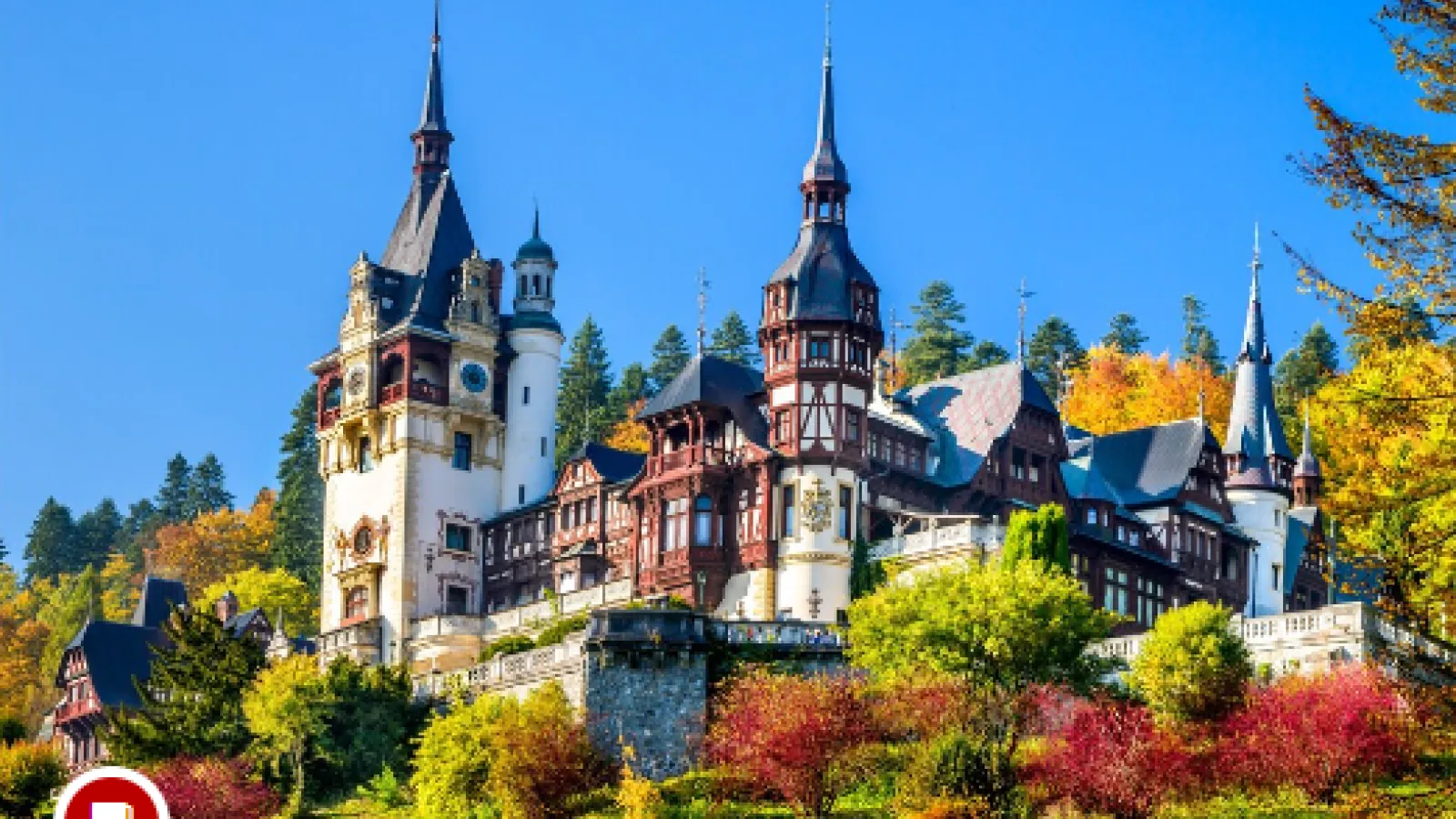 A hillside castle in the Neo-Renaissance style surrounded by trees of varied coloring