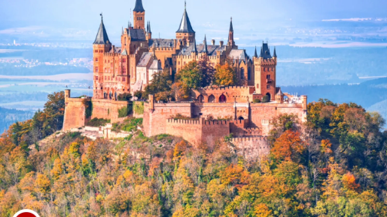 A castle on a hill surrounded by trees of various colors