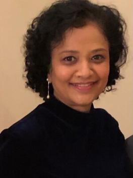 Smiling woman with dark hair and a dark sweater (Madhura Pradhan)
