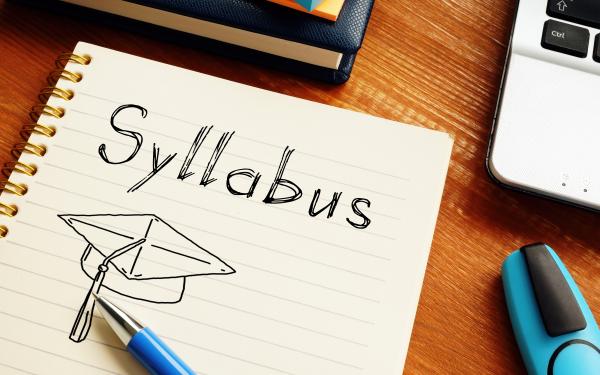 notebook with the word "syllabus" written on it and a pen resting on the notebook