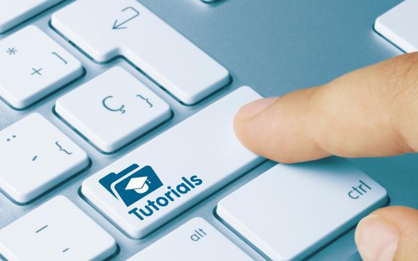 finger pressing key on laptop keyboard labeled "tutorials"