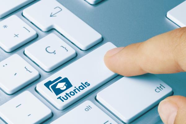 finger pressing key on laptop keyboard labeled "tutorials"