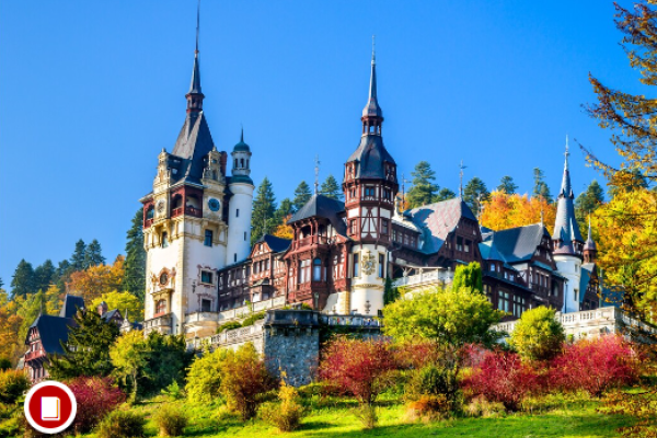 A hillside castle in the Neo-Renaissance style surrounded by trees of varied coloring