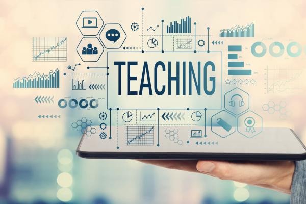 A tablet with the word "Teaching" hovering over it surrounded by digital icons