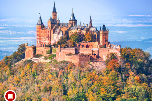 A castle on a hill surrounded by trees of various colors